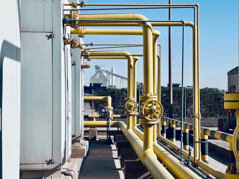 Yellow gas pipework and valves running along a terminal walkway.